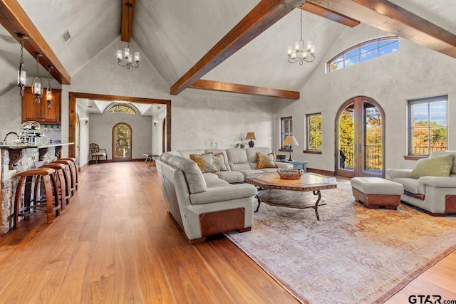 living room featuring high vaulted ceiling, a notable chandelier, and light wood-type flooring