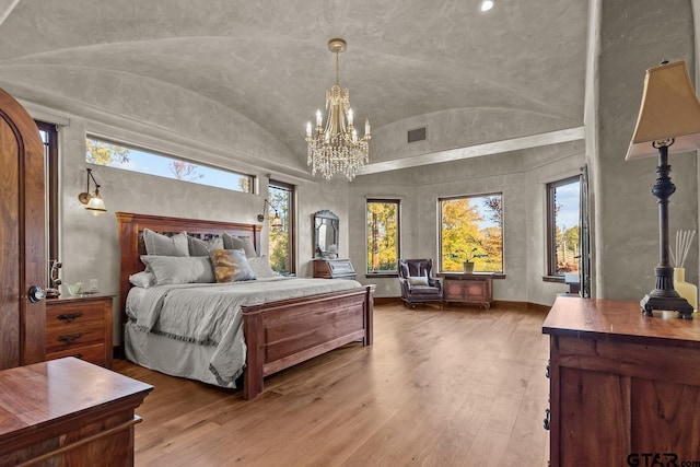 bedroom with lofted ceiling, a chandelier, and light hardwood / wood-style floors