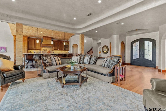 living room with light hardwood / wood-style flooring, french doors, and decorative columns