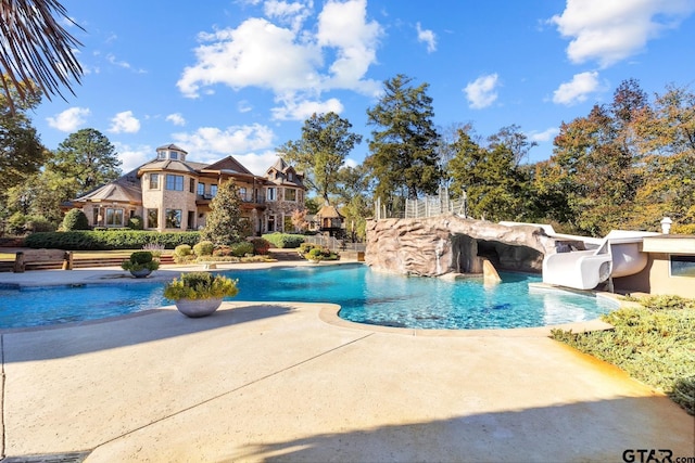 view of pool with a patio area, a water slide, and pool water feature