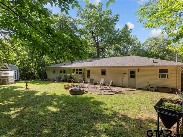 415 Lakeshore Dr, Palestine, TX 75801 - back of house featuring a patio, an outdoor structure, a yard, a shed, and a fire pit