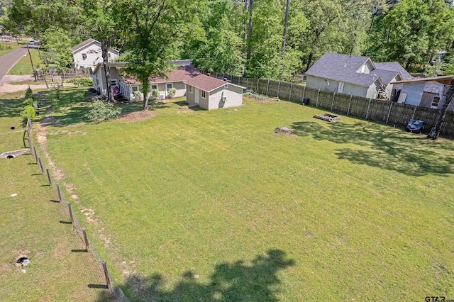 view of yard with a shed, a fenced backyard, and an outbuilding
