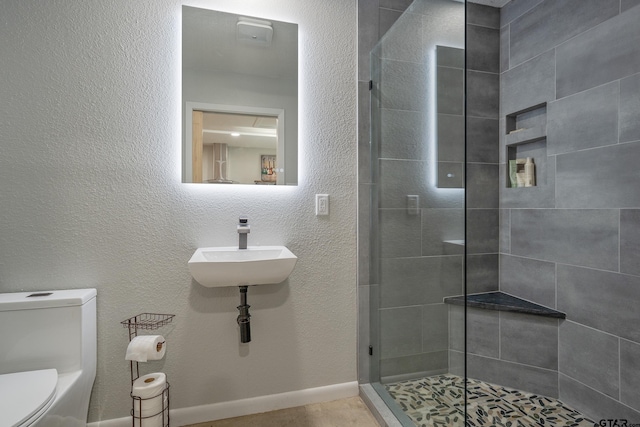 bathroom featuring toilet, a sink, and a stall shower