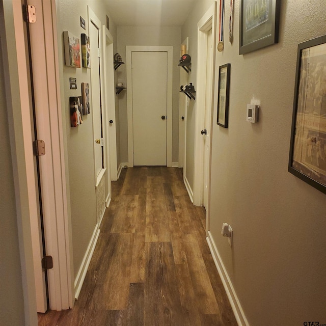 hall featuring baseboards and dark wood-style flooring