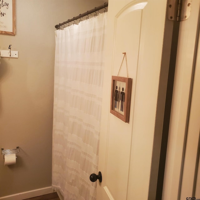 bathroom featuring curtained shower and baseboards