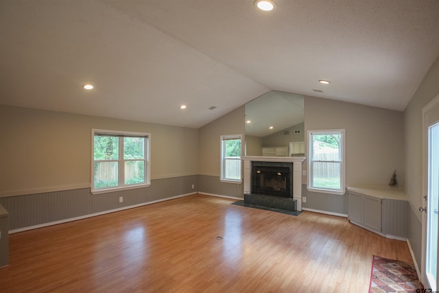 21298 Dogwood Dr, Flint, TX 75762 - unfurnished living room with light wood-style flooring, a wainscoted wall, a tile fireplace, lofted ceiling, and recessed lighting