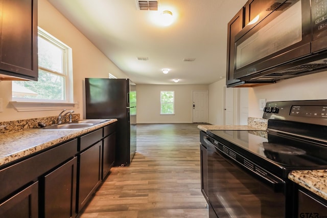 2525 N Tenneha Ave, Tyler, TX 75702 - kitchen with black appliances, light wood-type flooring, and dark brown cabinetry