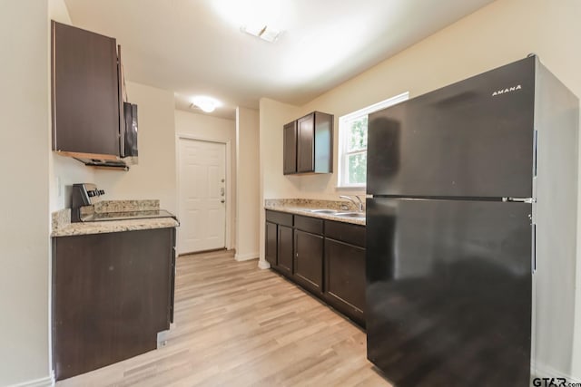 2525 N Tenneha Ave, Tyler, TX 75702 - kitchen featuring freestanding refrigerator, range, light countertops, dark brown cabinets, and light wood-style floors
