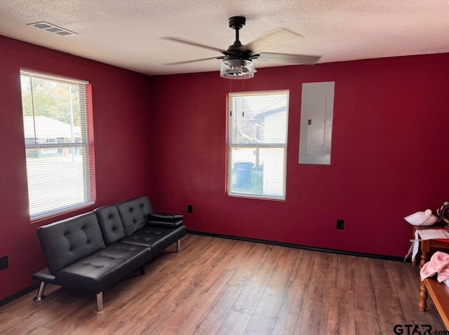 living area featuring electric panel, ceiling fan, a textured ceiling, and hardwood / wood-style floors