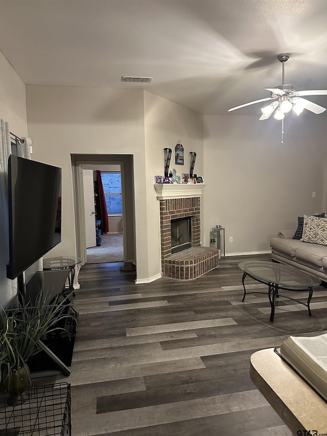 living area featuring visible vents, baseboards, ceiling fan, a fireplace, and wood finished floors