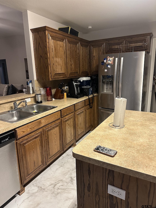 kitchen featuring a sink, light countertops, marble finish floor, and stainless steel appliances