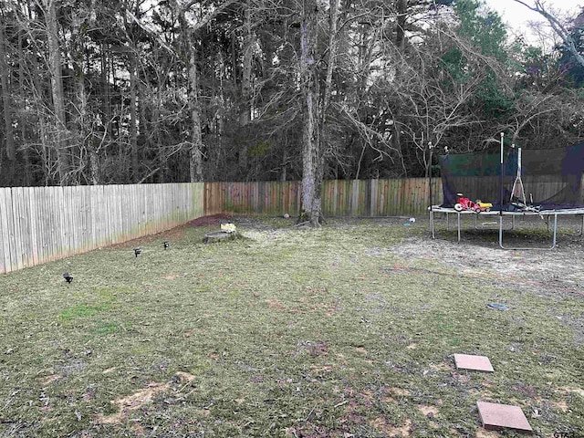 view of yard featuring a trampoline and a fenced backyard