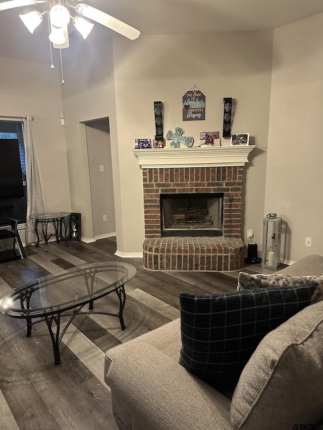 living area with a fireplace, baseboards, ceiling fan, and wood finished floors