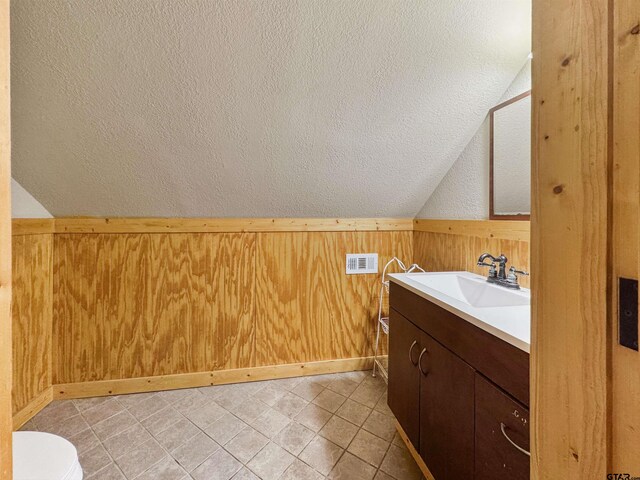 15250 Fm 858, Athens, TX 75752 - bathroom featuring wood walls, lofted ceiling, vanity, toilet, and a wainscoted wall