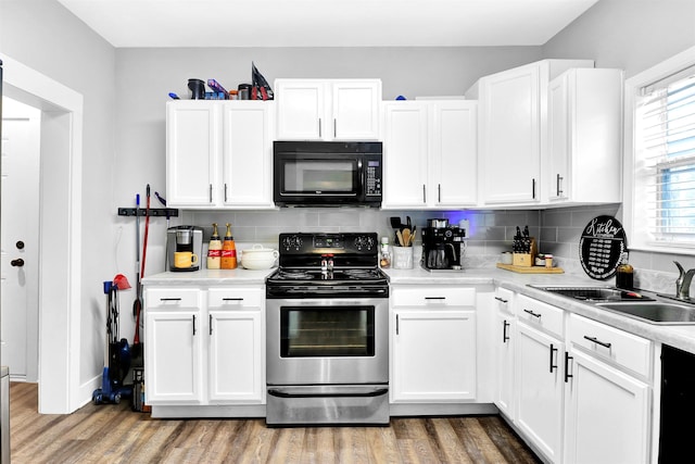 kitchen with stainless steel range with electric stovetop, backsplash, white cabinets, sink, and wood-type flooring