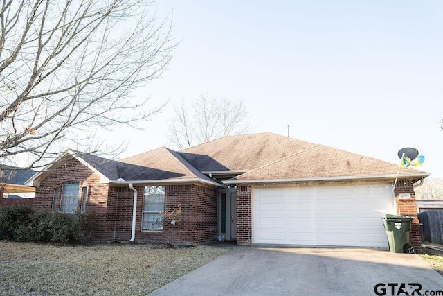 ranch-style home with brick siding, driveway, an attached garage, and roof with shingles