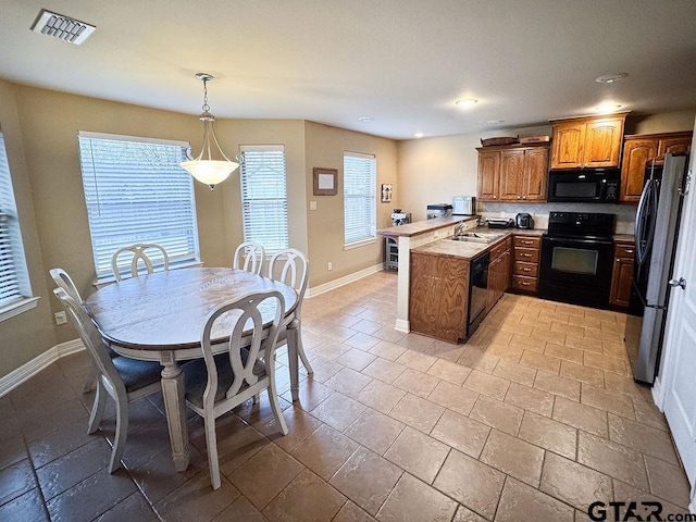 kitchen featuring baseboards, visible vents, a peninsula, and black appliances