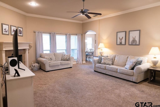 carpeted living area with arched walkways, visible vents, a tiled fireplace, ornamental molding, and ceiling fan