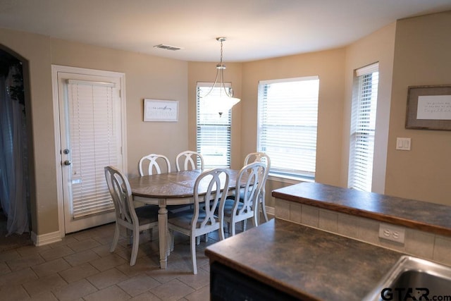 dining area featuring tile patterned flooring, visible vents, arched walkways, and baseboards