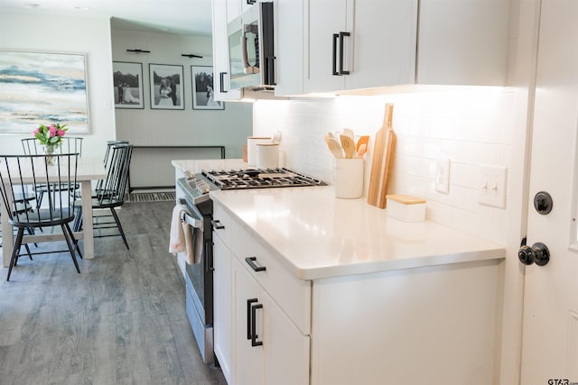 8116 Jewell Ln, Tyler, TX 75703 - kitchen featuring appliances with stainless steel finishes, tasteful backsplash, wood finished floors, white cabinets, and light countertops