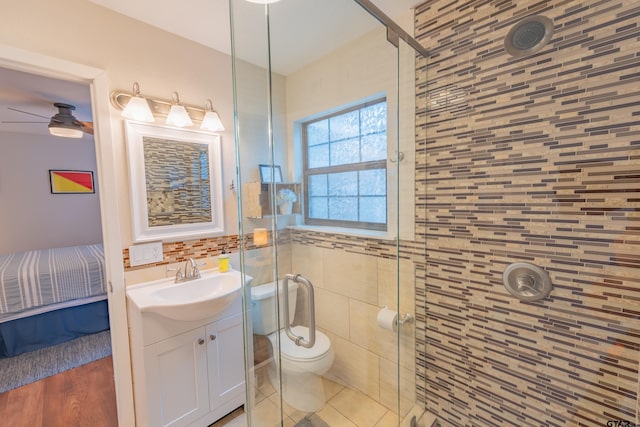 bathroom featuring a shower with door, ceiling fan, hardwood / wood-style floors, vanity, and toilet