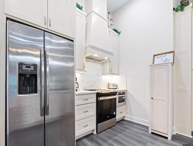 9109 Long Br, Tyler, TX 75703 - kitchen featuring appliances with stainless steel finishes, premium range hood, light wood-style floors, tasteful backsplash, and white cabinetry