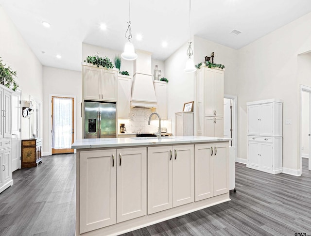 9109 Long Br, Tyler, TX 75703 - kitchen featuring stainless steel refrigerator with ice dispenser, dark wood-type flooring, custom exhaust hood, backsplash, and an island with sink