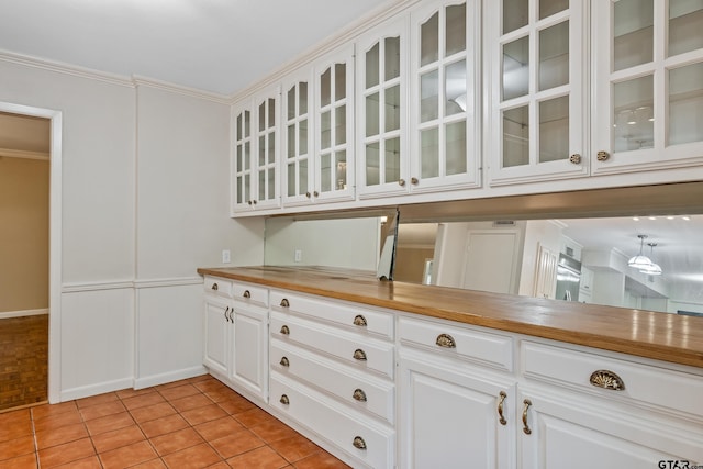 725 Purdue Dr, Tyler, TX 75701 - kitchen with a decorative wall, glass insert cabinets, crown molding, white cabinets, and butcher block countertops