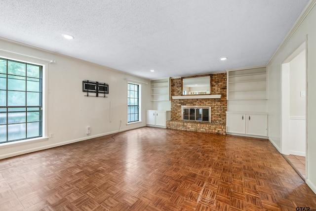 725 Purdue Dr, Tyler, TX 75701 - unfurnished living room featuring a textured ceiling, built in shelves, a fireplace, ornamental molding, and recessed lighting