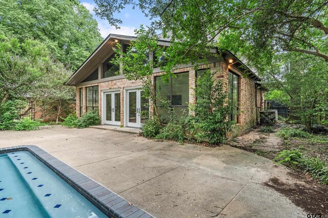 725 Purdue Dr, Tyler, TX 75701 - back of property featuring french doors, a patio area, an empty pool, and brick siding