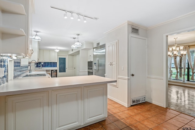 725 Purdue Dr, Tyler, TX 75701 - kitchen featuring stainless steel appliances, light countertops, a chandelier, backsplash, and rail lighting