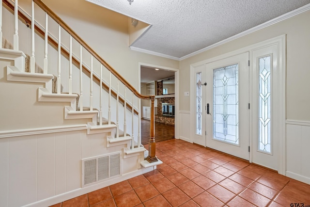 725 Purdue Dr, Tyler, TX 75701 - tiled entryway with a fireplace, a decorative wall, a textured ceiling, ornamental molding, and a wainscoted wall