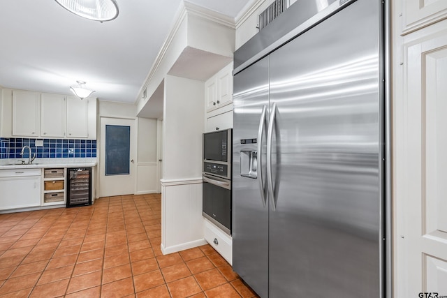 725 Purdue Dr, Tyler, TX 75701 - kitchen with appliances with stainless steel finishes, wine cooler, light countertops, crown molding, and light tile patterned floors