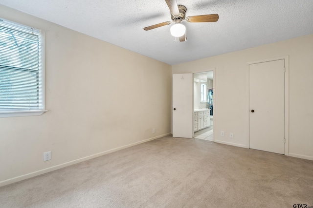 725 Purdue Dr, Tyler, TX 75701 - unfurnished bedroom featuring light carpet, a textured ceiling, ensuite bathroom, and a ceiling fan