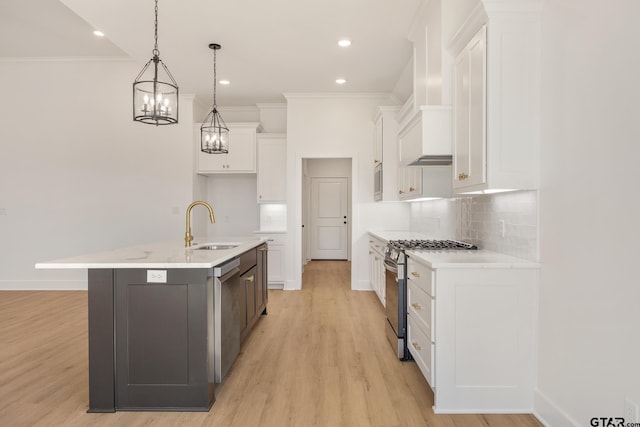 kitchen featuring hanging light fixtures, a kitchen island with sink, white cabinetry, and appliances with stainless steel finishes