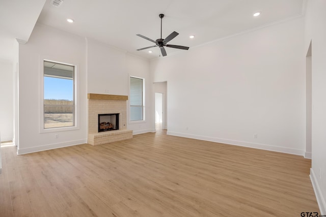 unfurnished living room with a fireplace, light hardwood / wood-style floors, ceiling fan, and ornamental molding