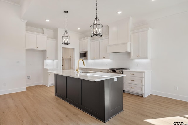 kitchen featuring sink, stainless steel appliances, white cabinetry, and a kitchen island with sink