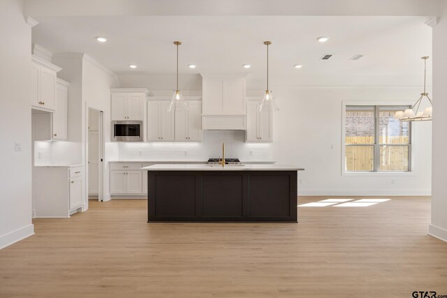 kitchen featuring stainless steel appliances, white cabinetry, sink, and a center island with sink