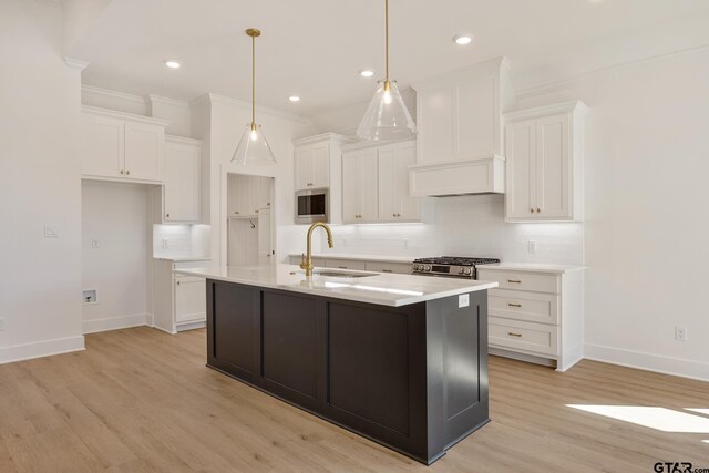 kitchen featuring hanging light fixtures, a center island with sink, ornamental molding, dishwasher, and white cabinets