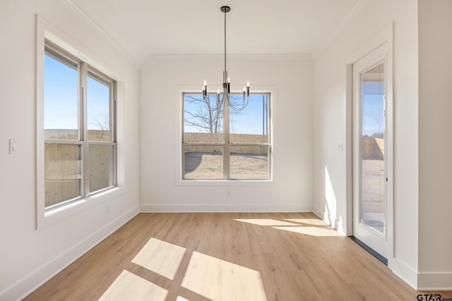 unfurnished dining area featuring light hardwood / wood-style floors, ornamental molding, and an inviting chandelier