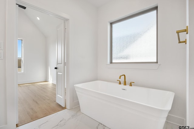 bathroom featuring a washtub and vaulted ceiling