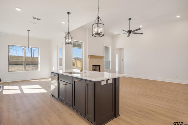 kitchen with sink, decorative light fixtures, dishwasher, and an island with sink