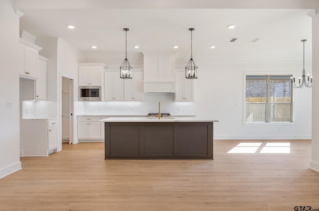 kitchen featuring white cabinets, light wood-type flooring, and stainless steel microwave