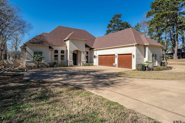 french provincial home with concrete driveway, a front yard, an attached garage, and stucco siding