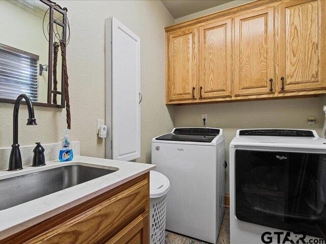 laundry area featuring cabinets, sink, and separate washer and dryer