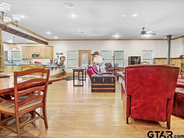 dining area featuring a wood stove, light hardwood / wood-style floors, ornamental molding, and ceiling fan