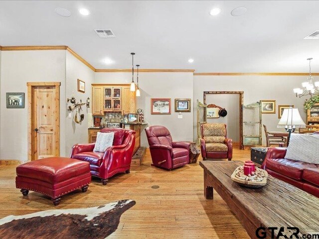 living room featuring light hardwood / wood-style floors, a chandelier, and ornamental molding