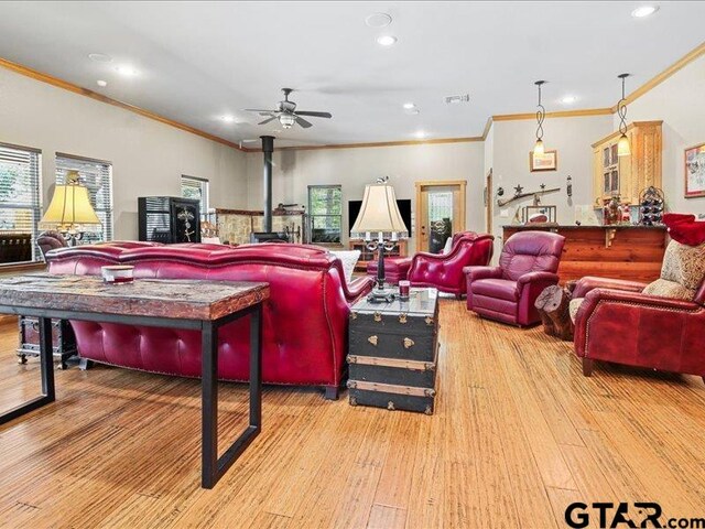 playroom featuring ceiling fan, light hardwood / wood-style flooring, a wood stove, and ornamental molding