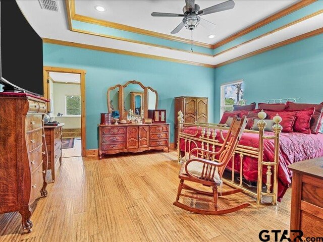 bedroom featuring light hardwood / wood-style floors, ceiling fan, ornamental molding, and a tray ceiling