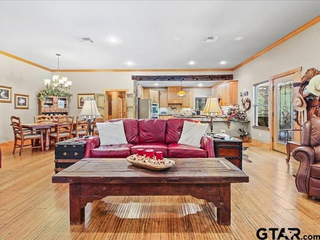 living room featuring ornamental molding, light hardwood / wood-style floors, and a chandelier